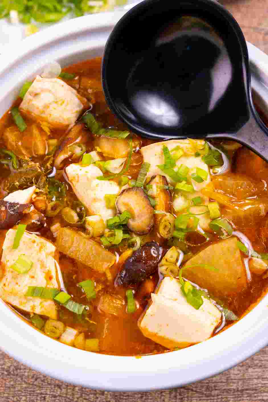 Korean Tofu Soup (Soondubu Jjigae) Recipe: Serve the Korean tofu soup (soondubu) drizzled with sesame oil and garnished with sliced green onions.