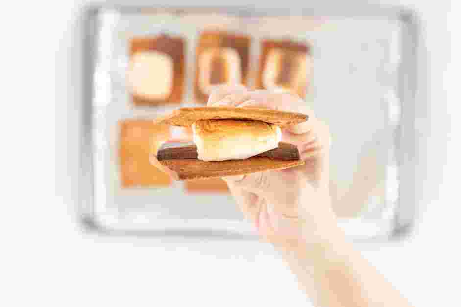 Smores in the Oven Recipe: Remove the sheet pan from the oven and press the top graham cracker halves onto each marshmallow.