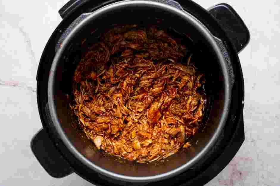 Instant Pot Chicken Tacos Recipe: Add the shredded chicken back to the pot and toss in the sauce.