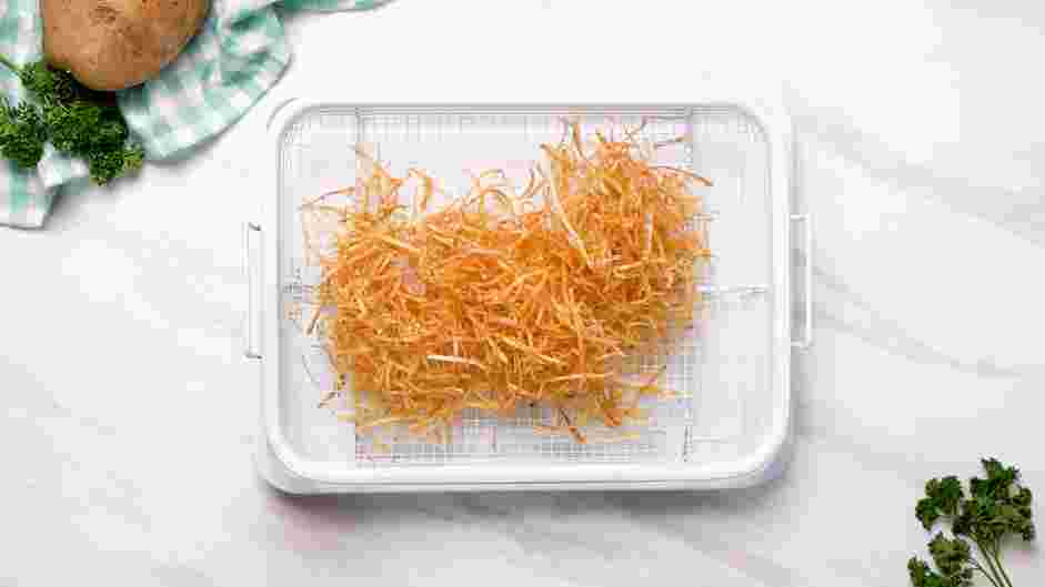 Shoestring Fries Recipe: Use a spider to remove the potatoes onto the wire rack and season immediately with garlic salt.