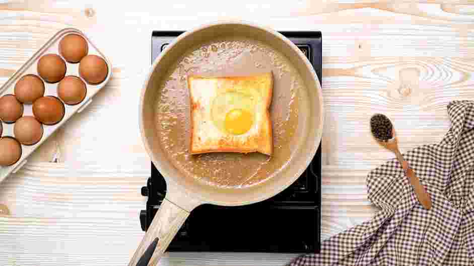 Egg in a Hole Recipe: Increase the heat to medium and crack one egg into the center hole of the bread and let cook for about 1 minute.