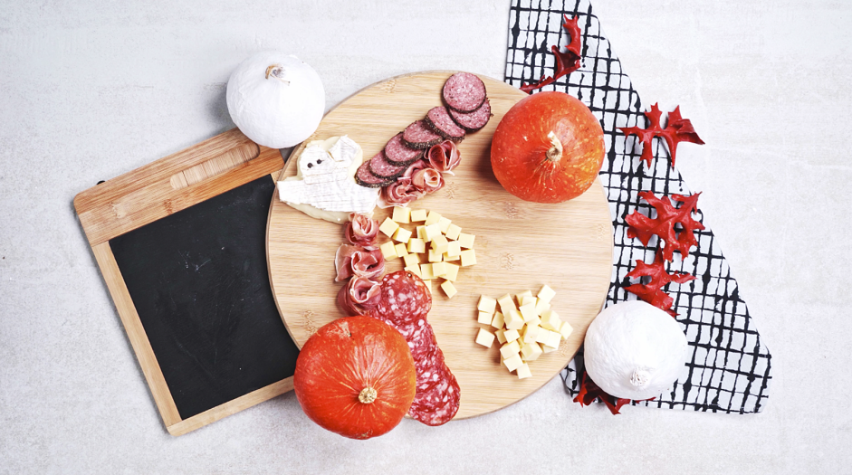 Halloween Charcuterie Board Recipe: Place about &frac34; of the prosciutto, hard salami and peppered salmi on the board.