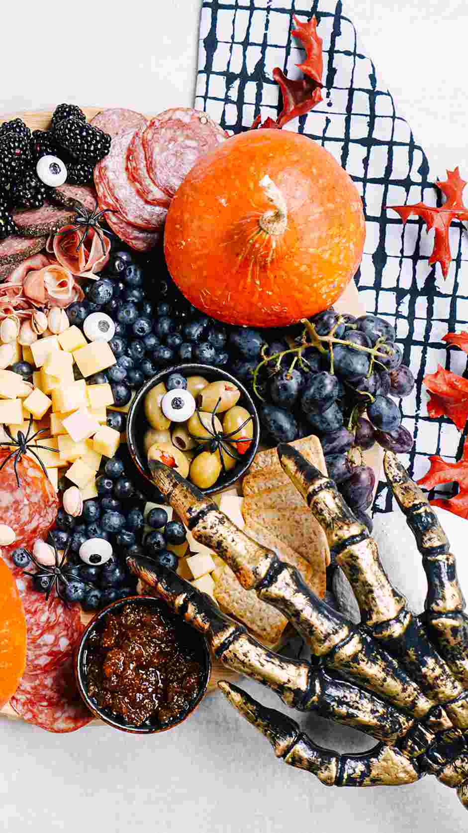 Halloween Charcuterie Board Recipe: Decorate with mini plastic spiders, candy eyes and a plastic skeleton hand for a spooky finish.