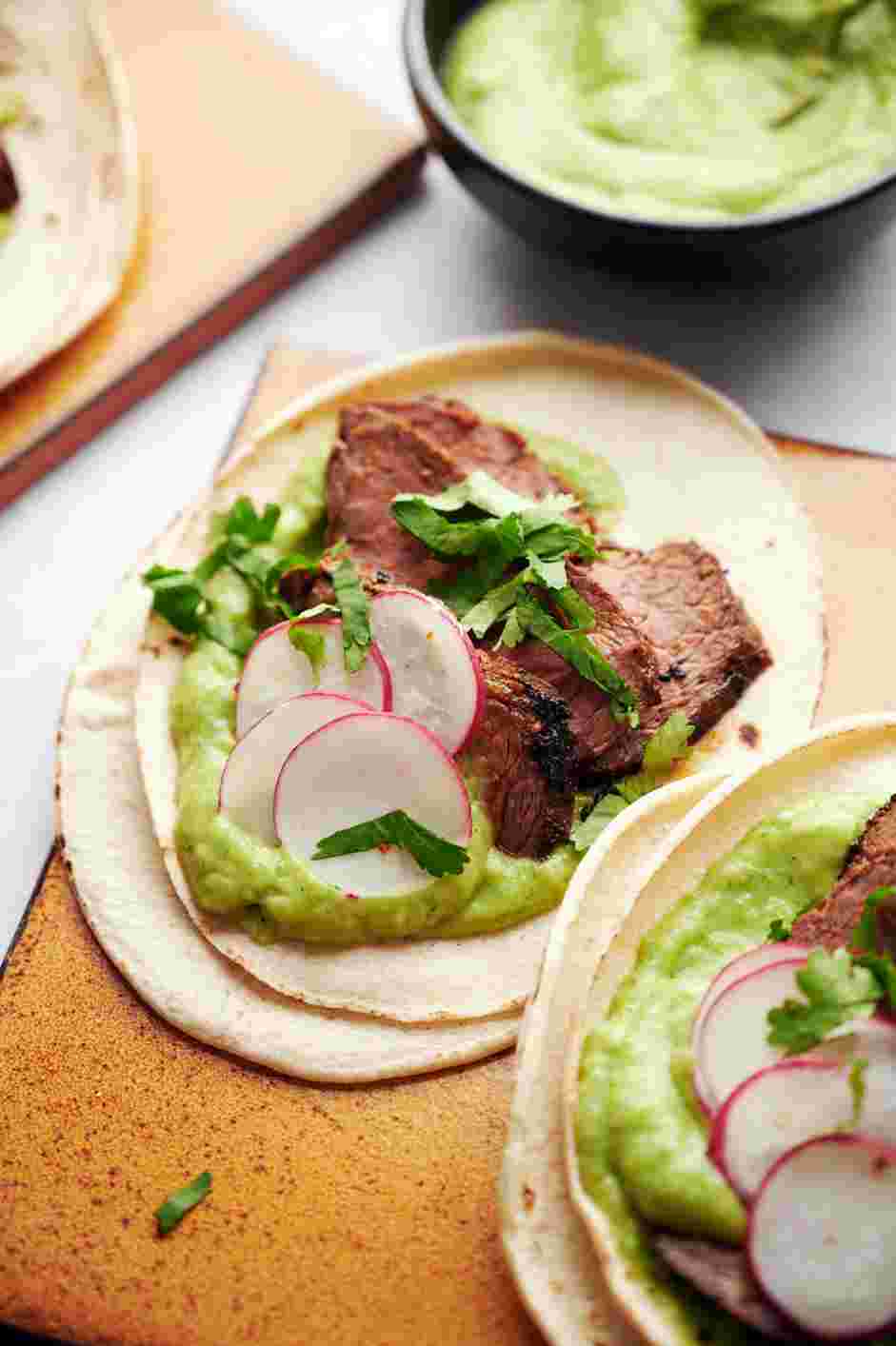 Skirt Steak Tacos with Avocado Crema Recipe: Stack two tortillas per taco (to prevent breakage) and add about 4-5 slices of steak to each taco.