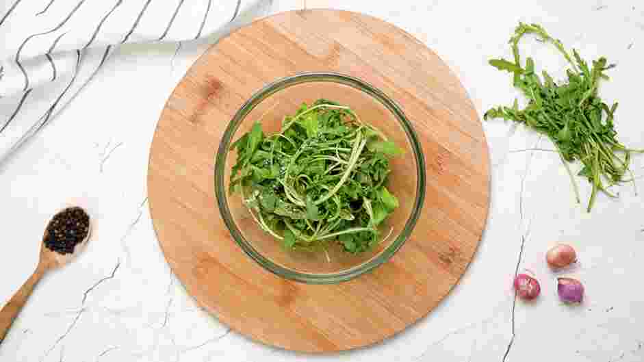 Beef Carpaccio Recipe: In a bowl, toss the baby arugula with truffle oil, salt and pepper.