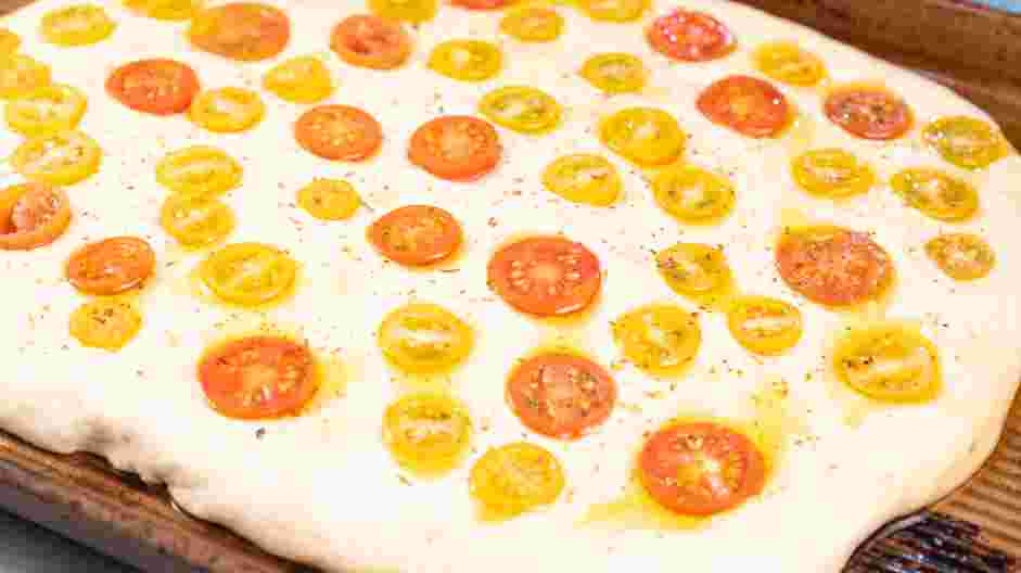 Focaccia Recipe: Once the dough is spread out, add the tomatoes by pressing them into the dough.