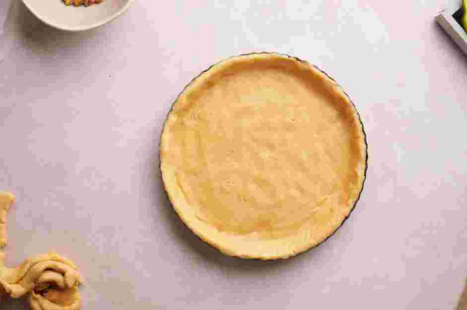 Fig Tart Recipe: Remove one of the parchment sheets and place the dough onto the tart pan.