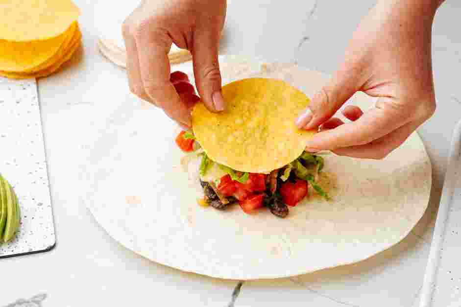 Black Bean Crunchwrap Supreme Recipe: Add the diced tomatoes, shredded romaine lettuce, and sliced avocados.