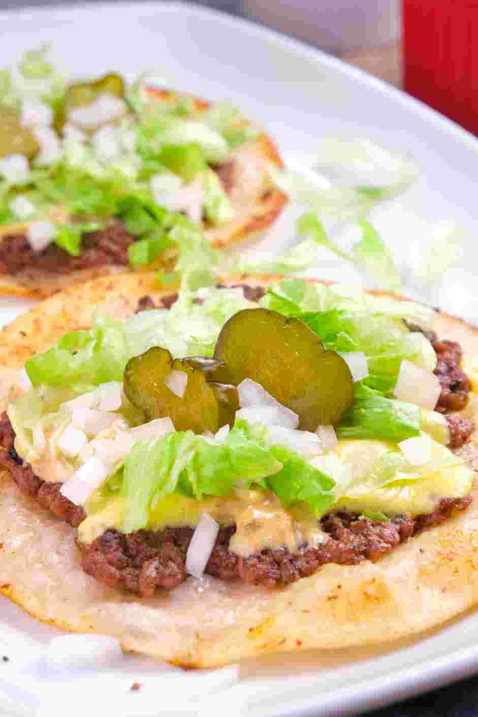 Smash Burger Tacos Recipe: Top with dill pickles, diced onion, shredded lettuce and a drizzle of the burger sauce.