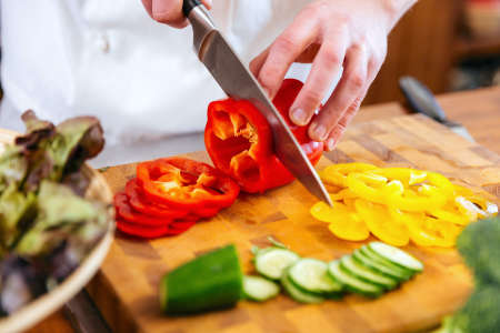 chef slicing red bell peppers