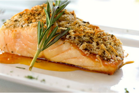 crusted salmon over sauce with rosemary sprig