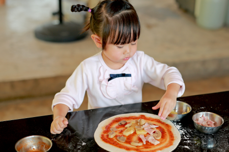 little girl making a homemade pizza