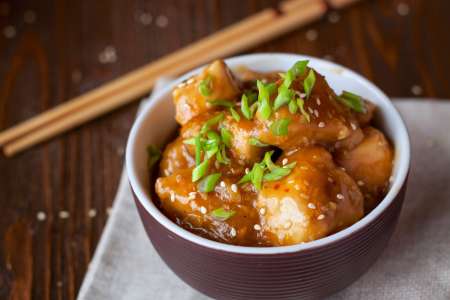 orange chicken in a bowl with chopsticks