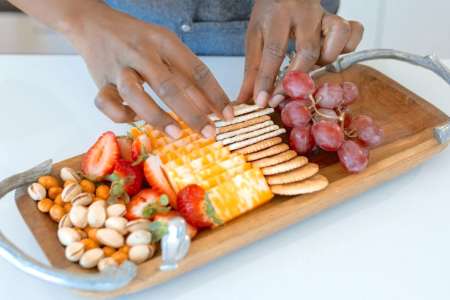 person arranging cheese and crackers on charcuterie board