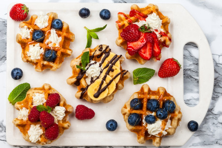 plate of belgian waffles with fruits and whipped cream