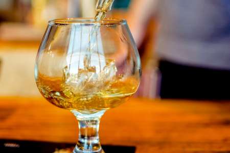 pouring whiskey into a sifter with ice