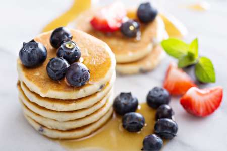 stack of buttermilk pancakes and berries with syrup