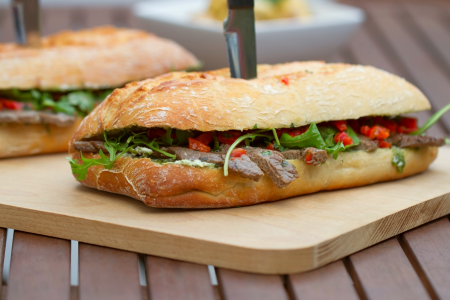 steak sandwich with a knife through it