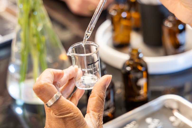 Dallas - erson measuring fragrance oil into a glass beaker during a candle making class Shot