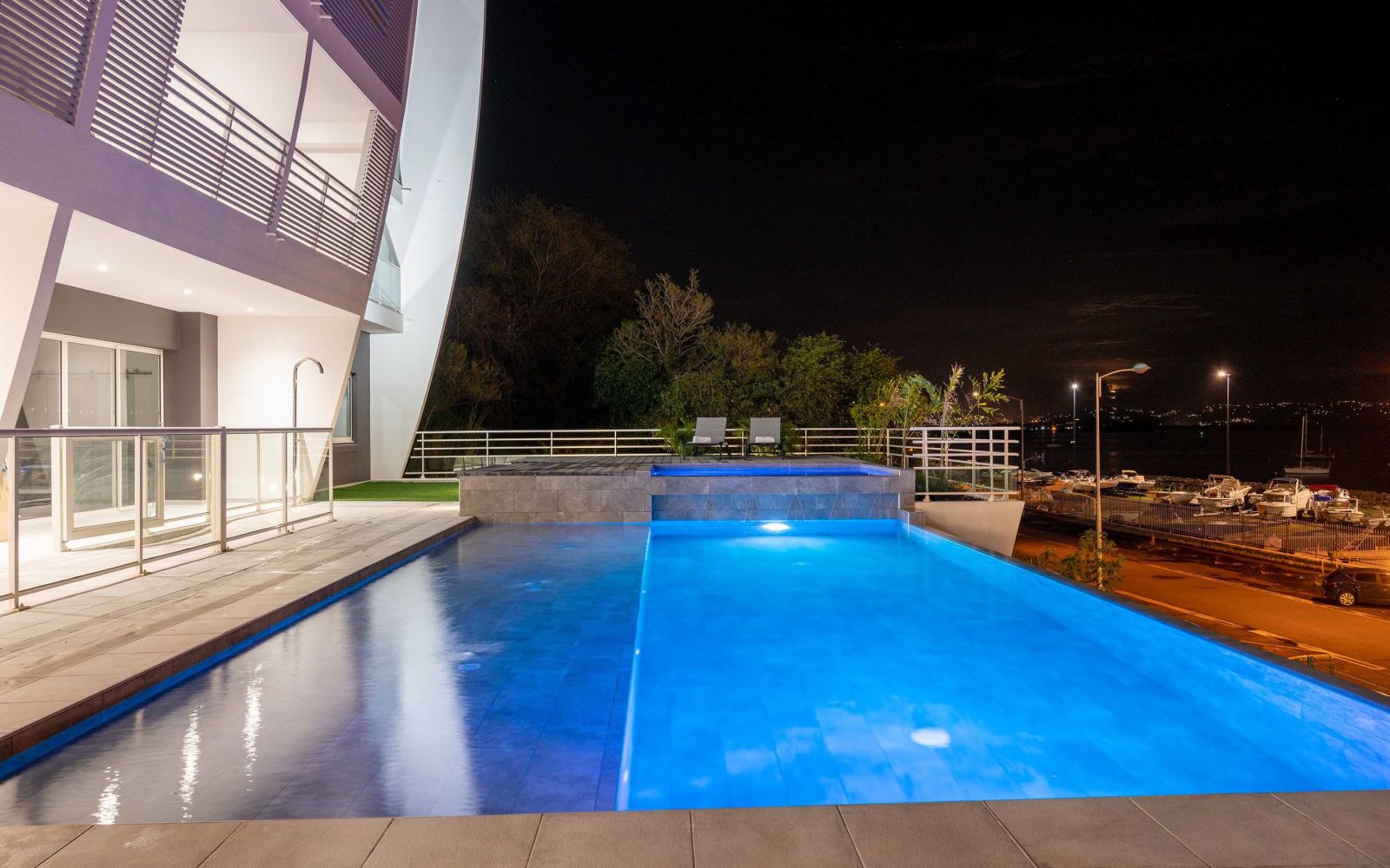 Illuminated outdoor infinity pool at B&B HOME hotel with night view of the marina and modern architecture
