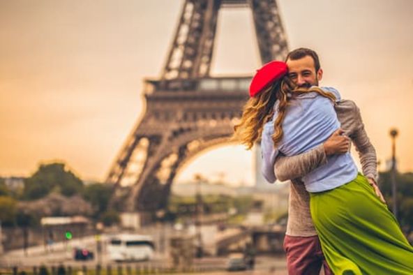 Un couple s'enlaçant devant la Tour Eiffel à Paris