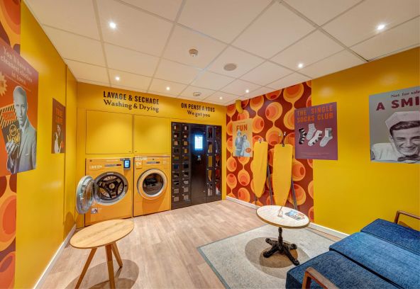 Laverie colorée de l'hôtel B&B HOME avec machines à laver et sèche-linge modernes pour les clients
