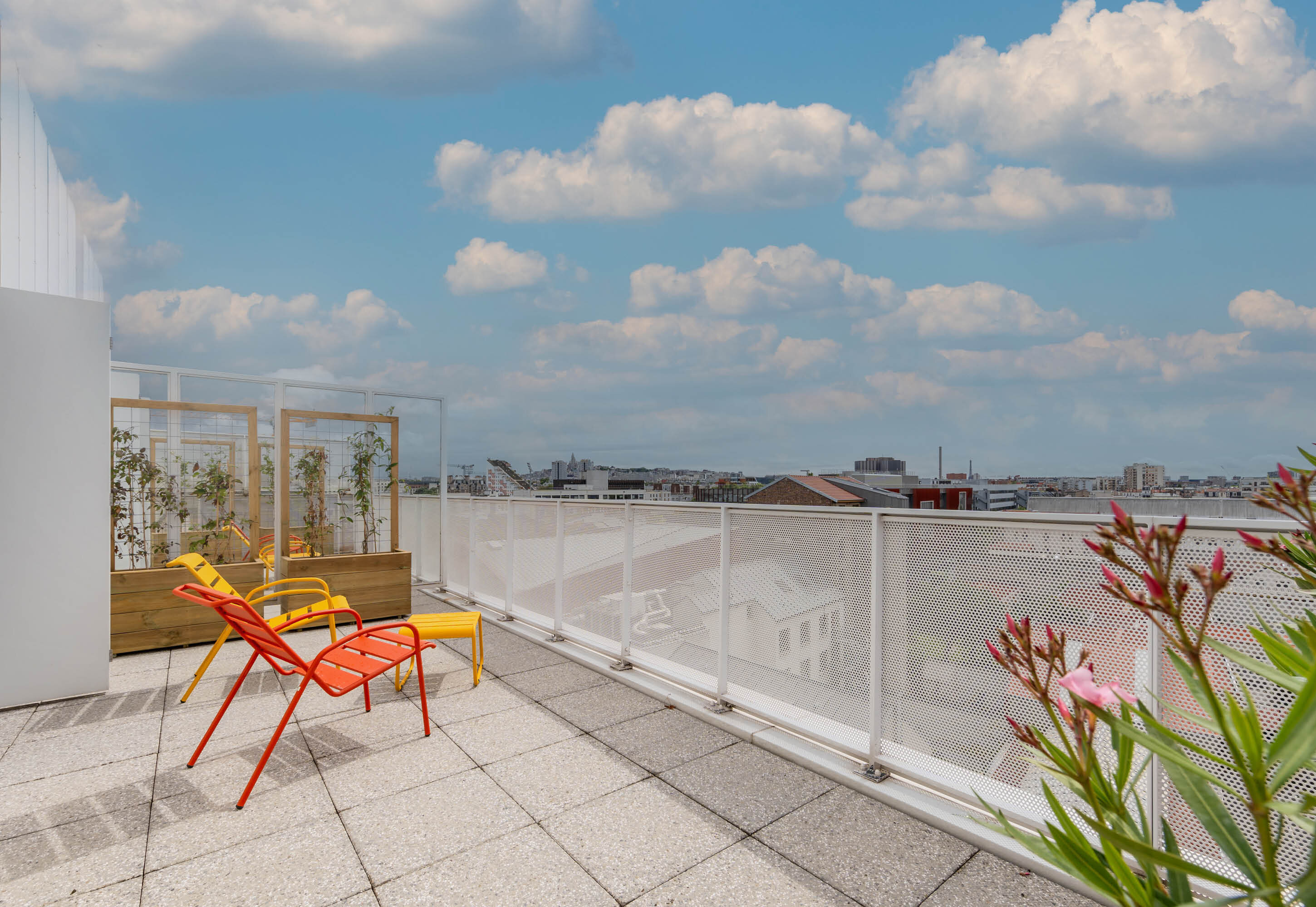 Sunny rooftop terrace at B&B HOME with colorful lounge chairs and panoramic city views