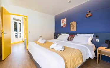 Chambre d'hôtel moderne au B&B HOME avec mur bleu vif et touches jaunes dotée d'un lit double confortable