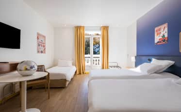 Chambre triple moderne à l'hôtel B&B HOME avec deux lits simples et un lit d'appoint rideaux jaunes et bureau