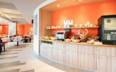 Modernes Frühstücksbuffet im B&B HOME mit frischem Gebäck Brot und Obst in einem hellen Speisesaal