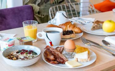 Leckeres kontinentales Frühstück im B&B HOME mit frischem Gebäck Eiern Speck und gesundem Müsli