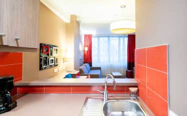 Modern hotel apartment kitchenette with sink overlooking a cozy living area at B&B HOME