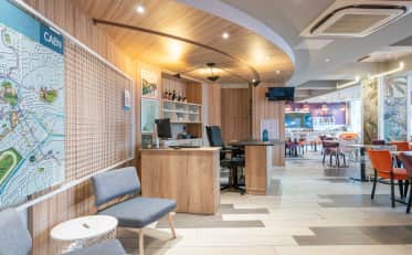 Moderna reception e hall dell'hotel con decorazioni in legno, posti a sedere e una mappa della città di Caen sulla parete.