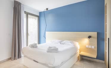 Modern hotel room at B&B HOME with a comfortable double bed and blue accent wall featuring a balcony access