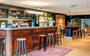 Elegante bar dell'hotel B&B HOME con bancone in legno e sgabelli in un'accogliente area lounge contemporanea