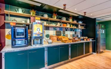 Moderno buffet colazione B&B HOME con macchina del caffè e pasticcini freschi su un elegante bancone piastrellato