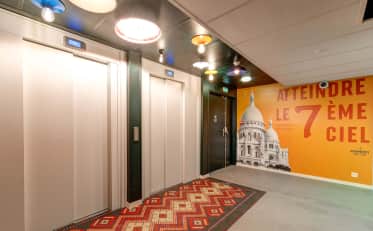 Moderna hall con ascensore presso B&B HOME con luci colorate a soffitto e murale artistico del Sacre Coeur a Parigi