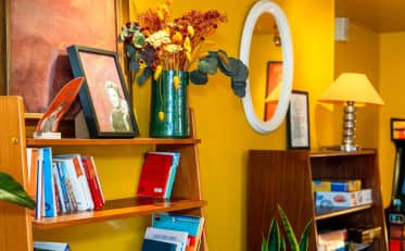 Accogliente area lounge con decorazioni vintage libri e pareti giallo vivace presso B&B HOME