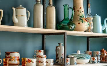 Stoviglie vintage e ceramiche decorative su scaffali in legno presso B&B HOME
