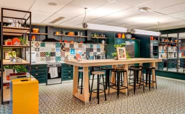 Moderna cucina comune presso B&B HOME con isola in legno e sgabelli da bar con eleganti piastrelle decorate
