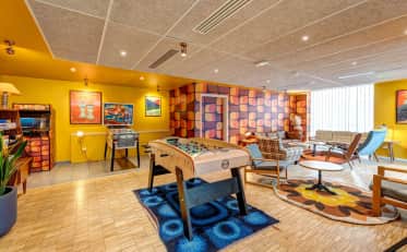Colorata lounge dell'hotel B&B HOME con biliardino giochi arcade e area salotto retrò per il relax degli ospiti