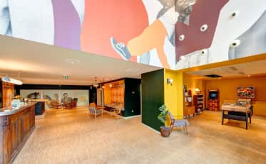Colorata e moderna hall di hotel presso B&B HOME con area lounge giochi arcade e arredamento vintage