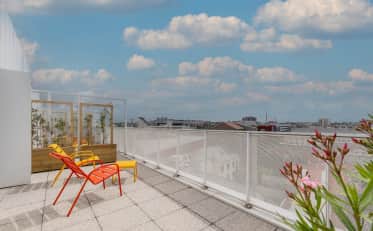 Terrazza panoramica soleggiata presso B&B HOME con sedie a sdraio colorate e vista sulla città