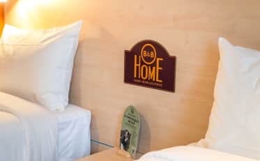 Interno di una moderna camera d'albergo presso B&B HOME con letti confortevoli e servizio di e-concierge