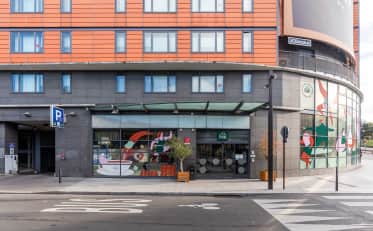 Modern exterior facade of B&B HOME hotel building with street entrance and artistic window decals