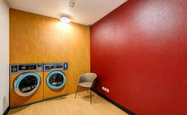 Self-service laundry room at B&B HOME with professional washing machines and a comfortable chair