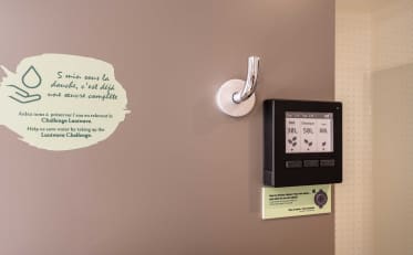 Umweltfreundliches Luniwave Wasserspargerät in einem B&B HOME Hotelbadezimmer zur Förderung nachhaltiger Praktiken