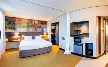 Modernes Hotelzimmer im B&B HOME mit bequemem Doppelbett und praktischer Kochnische