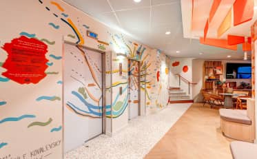 Moderner Hotel-Lobbybereich im B&B HOME mit künstlerischen Wandmalereien und Aufzugszugang in zeitgemäßem Design