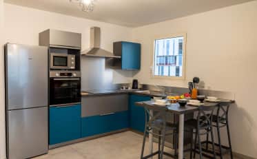 Modern kitchen in a B&B HOME apartment with stainless steel appliances and a dining area for guests